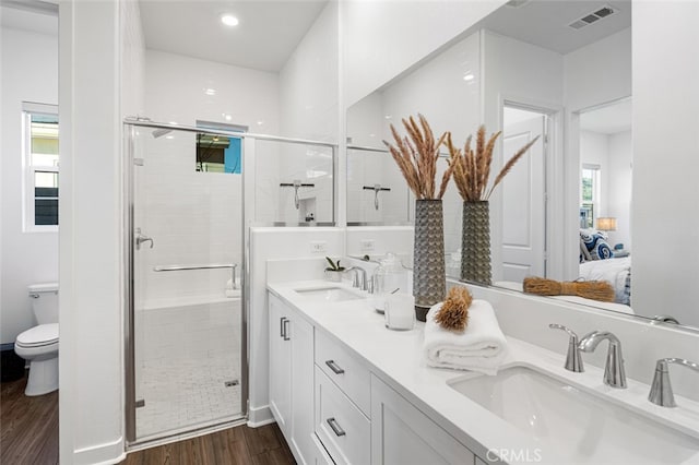 bathroom featuring hardwood / wood-style floors, vanity, walk in shower, toilet, and a healthy amount of sunlight