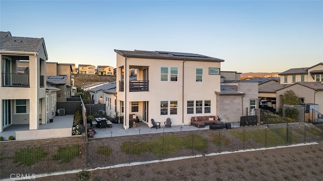 back house at dusk featuring outdoor lounge area, cooling unit, and solar panels