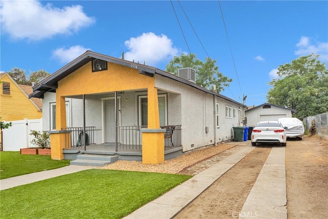 bungalow-style home with a front lawn, cooling unit, covered porch, and a garage