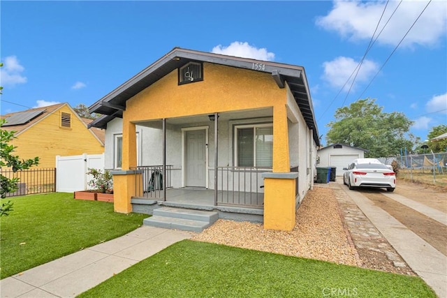 bungalow-style house with a front yard, a porch, an outdoor structure, and a garage