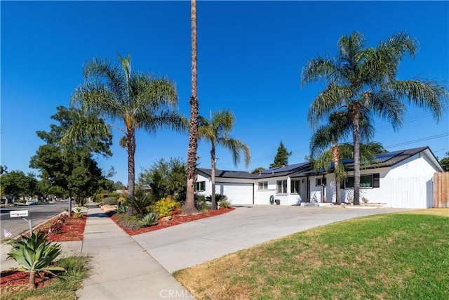 view of front of house featuring a front lawn, a garage, and solar panels