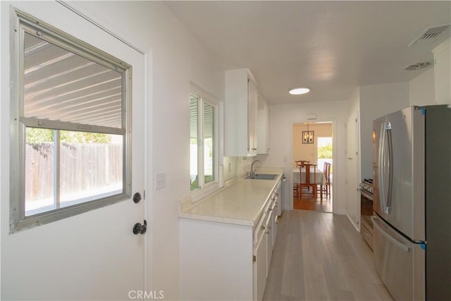 kitchen with white cabinets, appliances with stainless steel finishes, sink, and light wood-type flooring