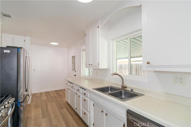 kitchen with white cabinets, light wood-type flooring, appliances with stainless steel finishes, and sink