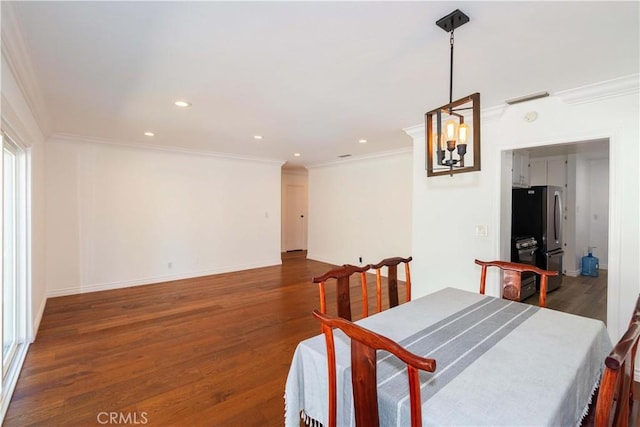 dining room featuring dark wood-type flooring, crown molding, and an inviting chandelier