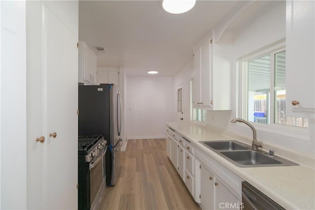 kitchen featuring gas range, dishwasher, white cabinets, and sink