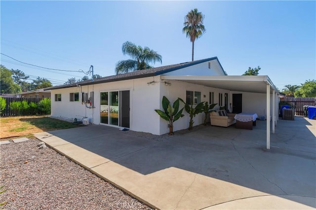 rear view of house with outdoor lounge area and a carport