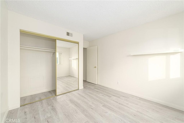 unfurnished bedroom with a closet, a textured ceiling, and light wood-type flooring