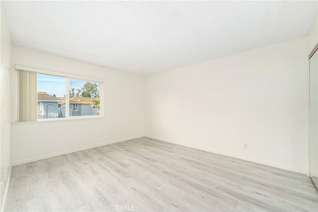 empty room with light hardwood / wood-style flooring and a textured ceiling