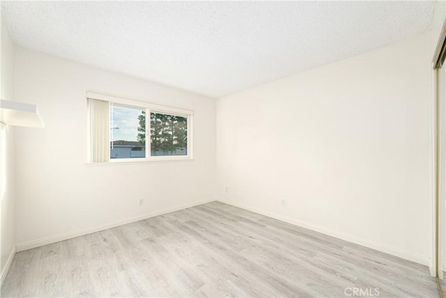 unfurnished room with light hardwood / wood-style floors and a textured ceiling