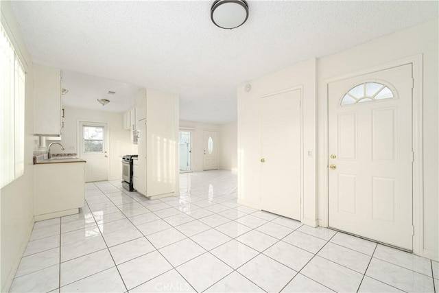 foyer with light tile patterned flooring, sink, and a textured ceiling