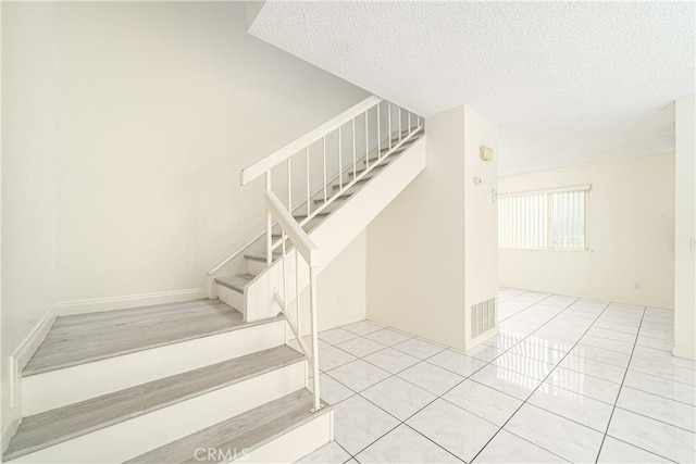 staircase featuring tile patterned flooring and a textured ceiling