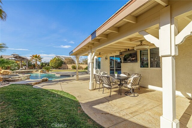 view of patio with ceiling fan and a swimming pool with hot tub