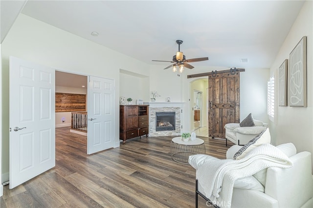 living room with ceiling fan, dark hardwood / wood-style floors, and a stone fireplace