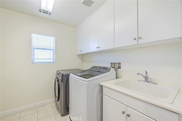 clothes washing area with cabinets, light tile patterned flooring, independent washer and dryer, and sink