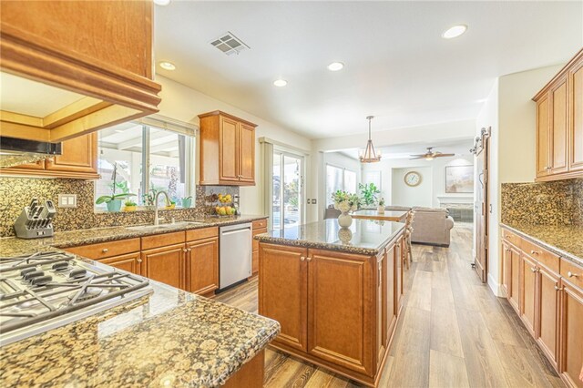 kitchen featuring pendant lighting, appliances with stainless steel finishes, a kitchen island, sink, and ceiling fan