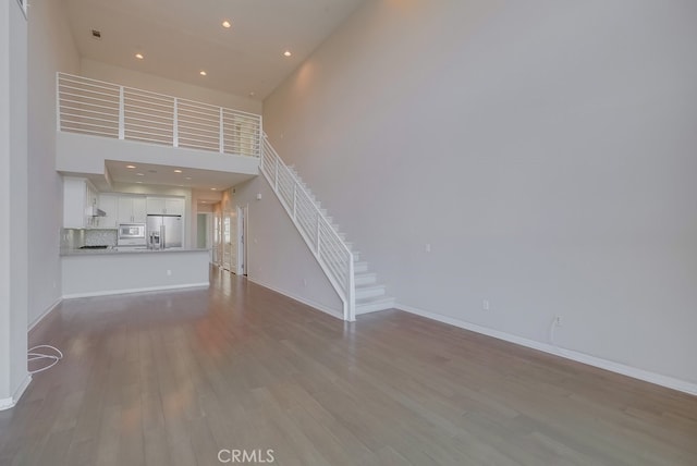 unfurnished living room with light wood-type flooring and a high ceiling