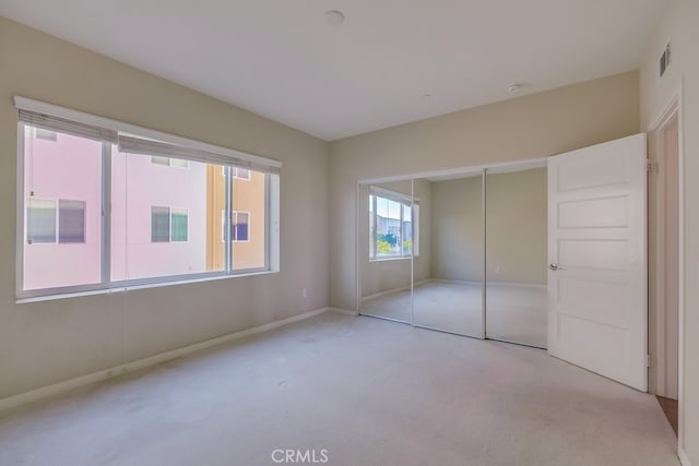 unfurnished bedroom featuring a closet and light colored carpet