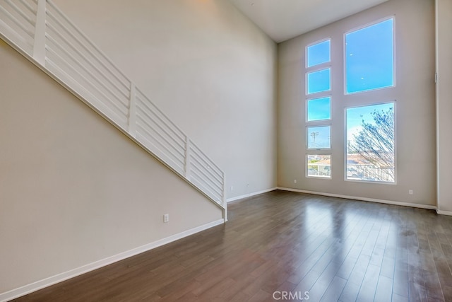 unfurnished living room with a high ceiling and dark hardwood / wood-style flooring