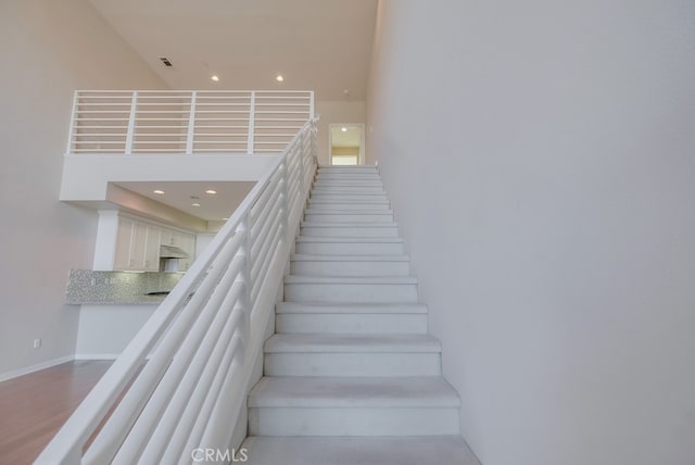 staircase with a high ceiling and hardwood / wood-style floors