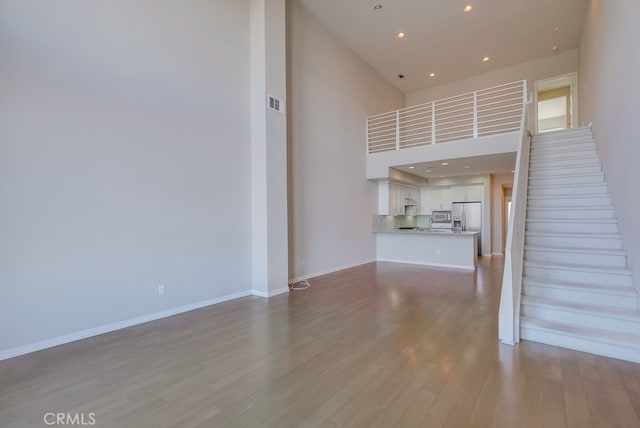 unfurnished living room featuring hardwood / wood-style flooring and a high ceiling