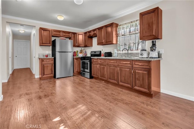 kitchen with light stone countertops, appliances with stainless steel finishes, light hardwood / wood-style floors, and sink