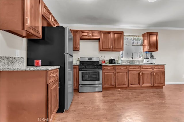 kitchen with light stone countertops, appliances with stainless steel finishes, sink, ornamental molding, and light hardwood / wood-style flooring