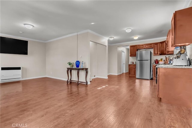 kitchen with light hardwood / wood-style floors, heating unit, light stone countertops, ornamental molding, and stainless steel refrigerator