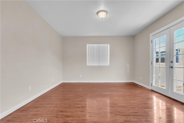 empty room featuring hardwood / wood-style floors, french doors, and a healthy amount of sunlight