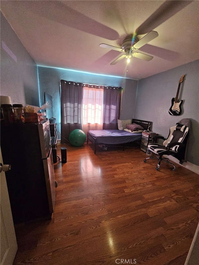 bedroom featuring ceiling fan, dark wood-type flooring, and stainless steel fridge