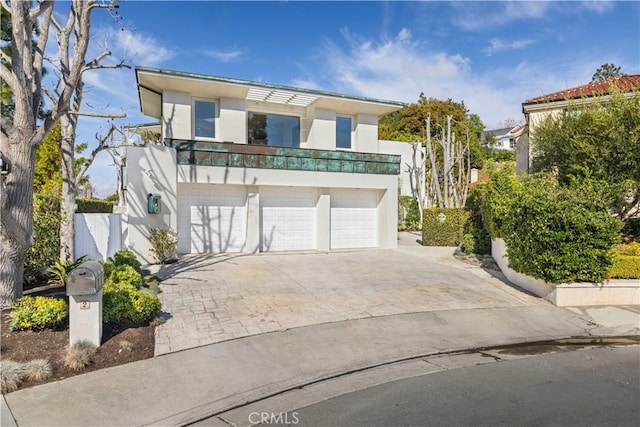 contemporary house featuring a garage, decorative driveway, and stucco siding