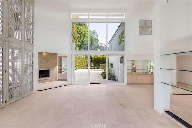 unfurnished living room with a high end fireplace and a towering ceiling