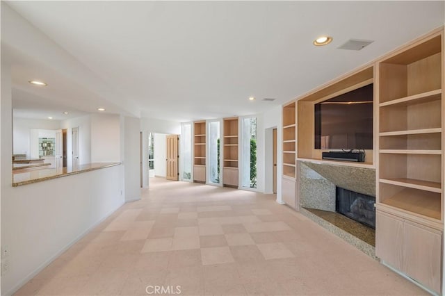 interior space featuring built in shelves, recessed lighting, a fireplace, and baseboards