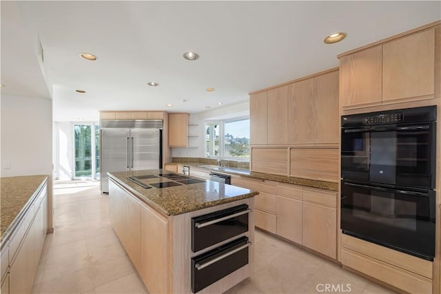 kitchen with stone counters, a center island, light brown cabinets, and black appliances