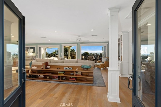 living room featuring decorative columns, ceiling fan, and light wood-type flooring