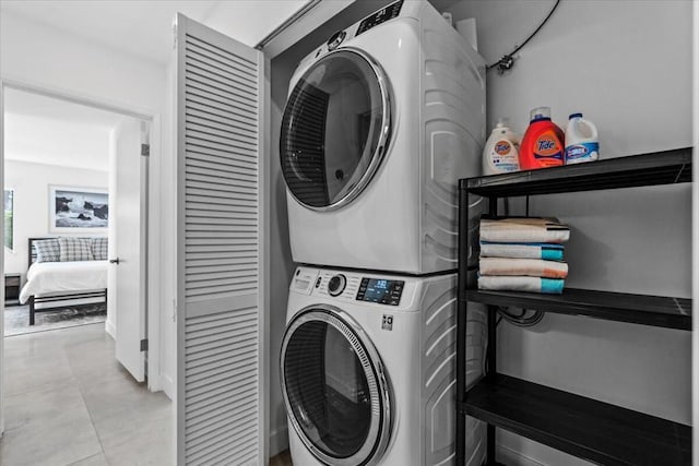 clothes washing area with light tile patterned floors and stacked washing maching and dryer