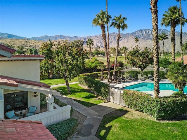 view of pool featuring a patio area, a mountain view, and a yard