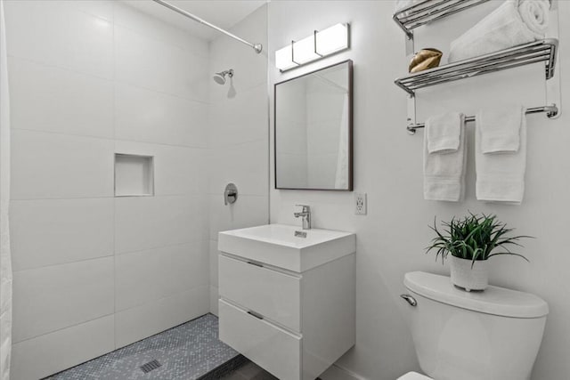 bathroom featuring toilet, vanity, and a tile shower