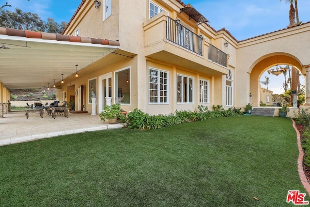 rear view of house with a yard, a patio area, and a balcony