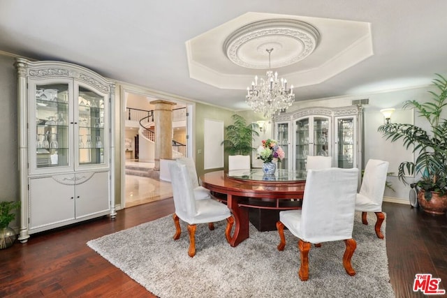 dining space with a tray ceiling, dark hardwood / wood-style floors, and a notable chandelier