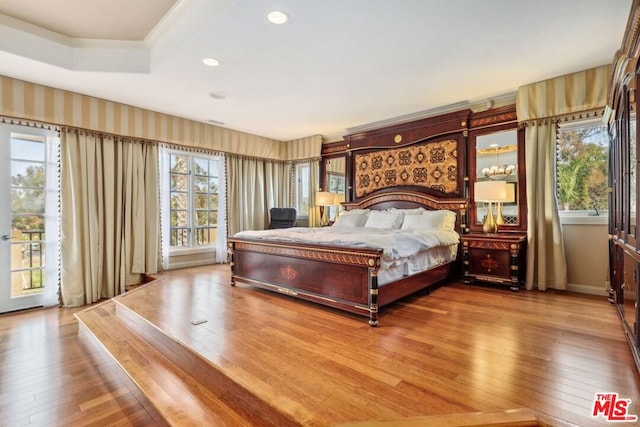 bedroom featuring crown molding, wood-type flooring, and a tray ceiling