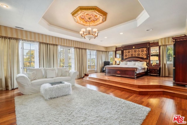 bedroom featuring a raised ceiling, an inviting chandelier, and hardwood / wood-style floors