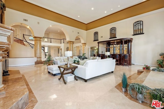 living room featuring ornate columns, ornamental molding, and a towering ceiling