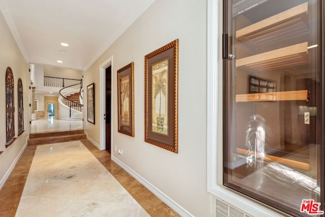 hall featuring light tile patterned floors and crown molding