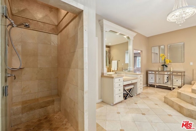 bathroom with tile patterned floors, a chandelier, tiled shower, and vanity