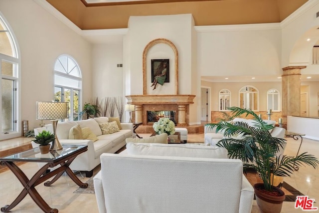 living room featuring decorative columns, a high ceiling, a high end fireplace, and ornamental molding