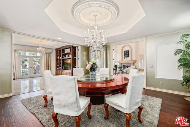 dining area featuring a raised ceiling, french doors, dark hardwood / wood-style floors, and crown molding