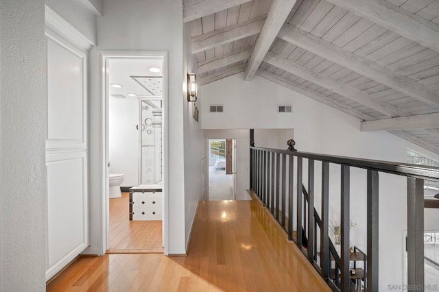 hallway featuring lofted ceiling with beams, wooden ceiling, and light hardwood / wood-style flooring