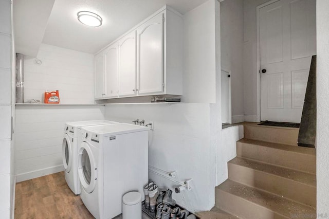 laundry room with washing machine and clothes dryer, cabinets, and light hardwood / wood-style flooring