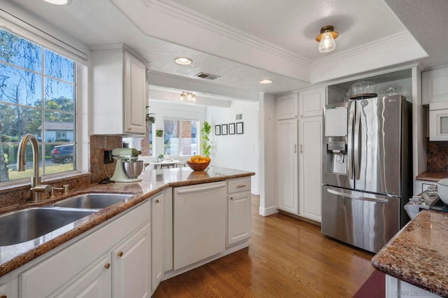 kitchen with sink, white cabinetry, light stone counters, white dishwasher, and stainless steel fridge with ice dispenser