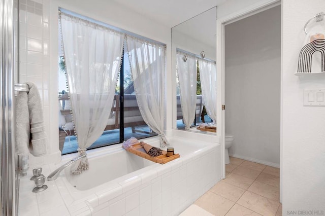 bathroom with toilet, tile patterned flooring, and tiled tub